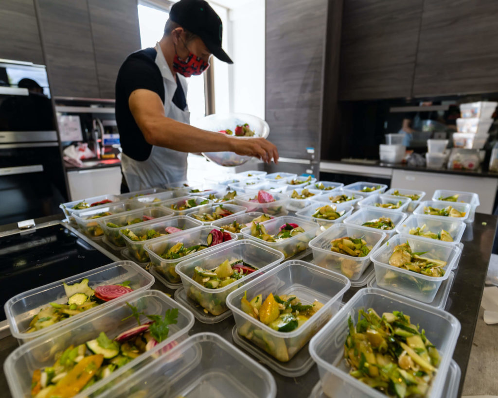 Man filling food containers with healthy, prepared meals