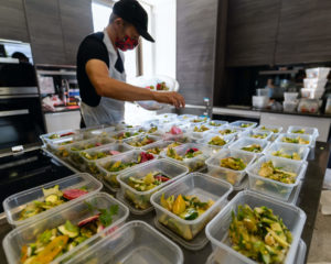 Man filling food containers with healthy, prepared meals