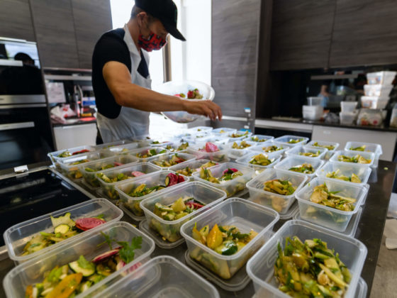 Man filling food containers with healthy, prepared meals
