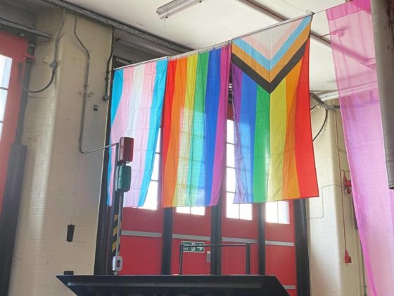 Image of Pride, trans and LGBTQIA+ flags hanging in a spacious hall