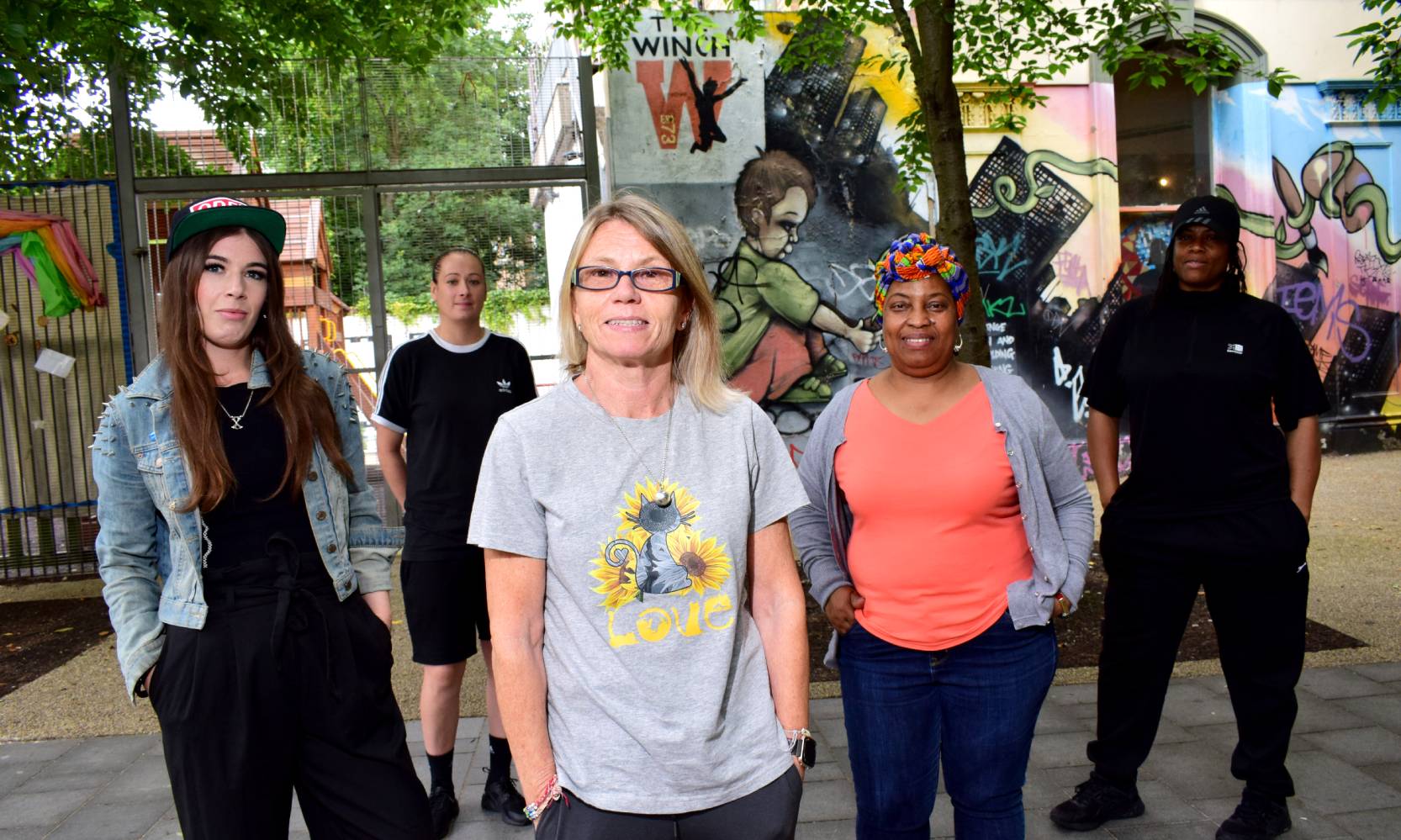 Group shot of young black and white women in front of a colourful painted building