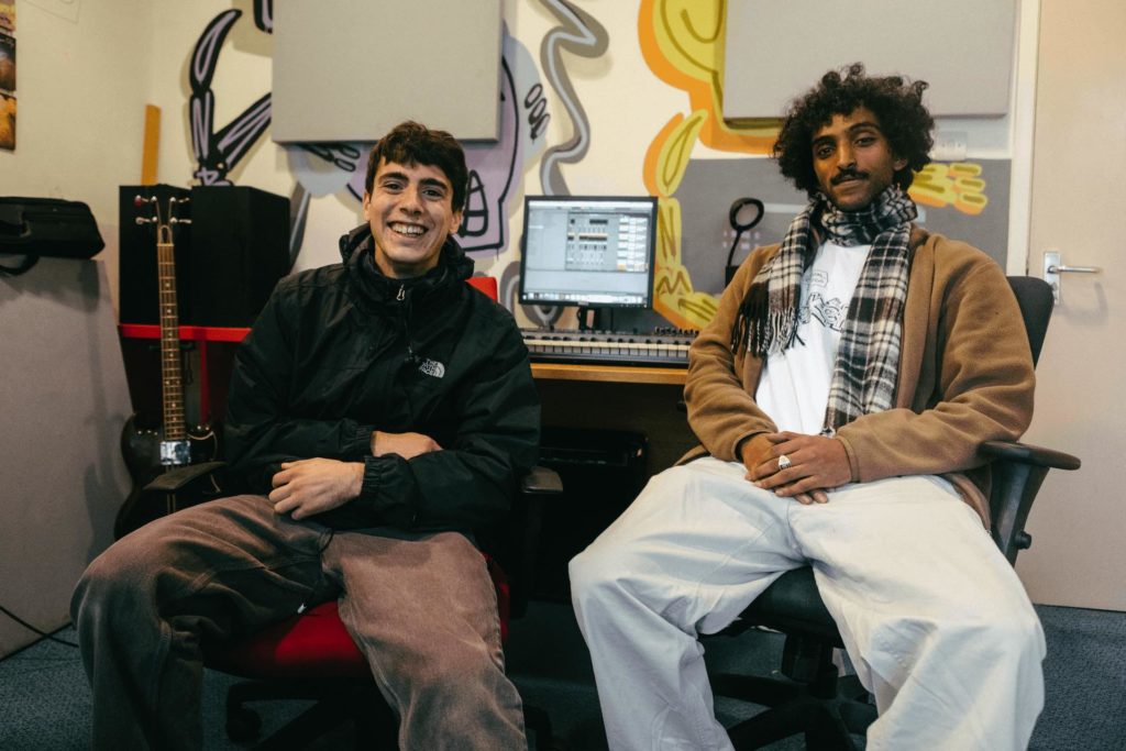 Two young men smiling and sitting in a music studio