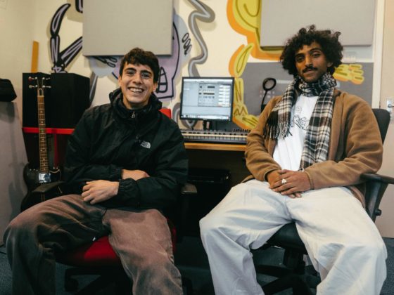 Two young men smiling and sitting in a music studio