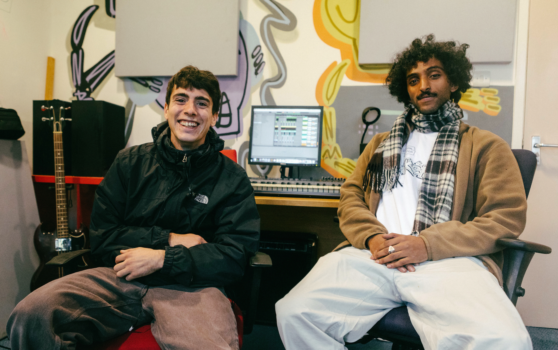 Two young men smiling in a music studio