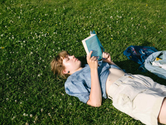 Girl reading a book, lying on grass
