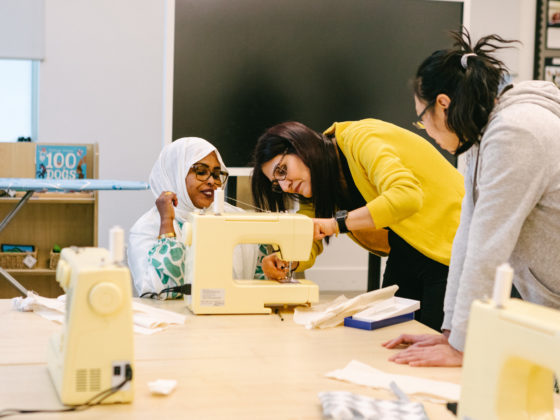 Two women work at a sewing machine