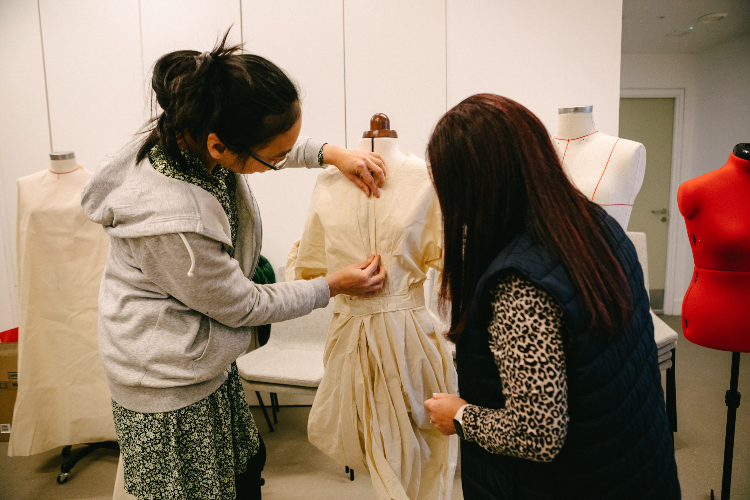 Two women design on a mannequin