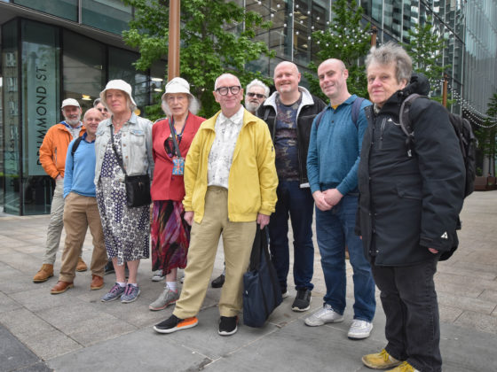 Chris stands in a group photo with nine members of the Curious Club outside the Old Diorama Arts Centre