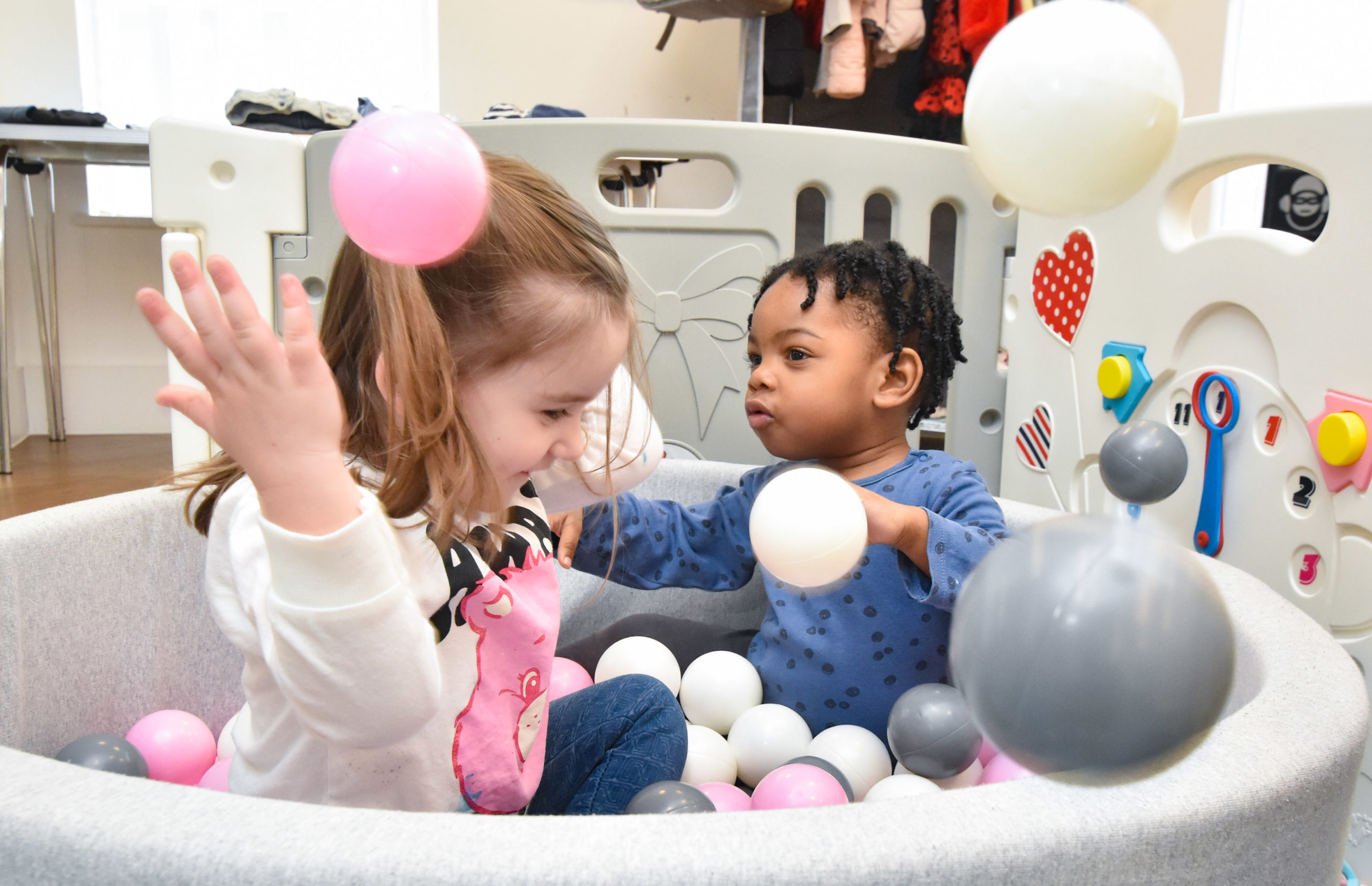 Two children enjoy the ball pit in the play area