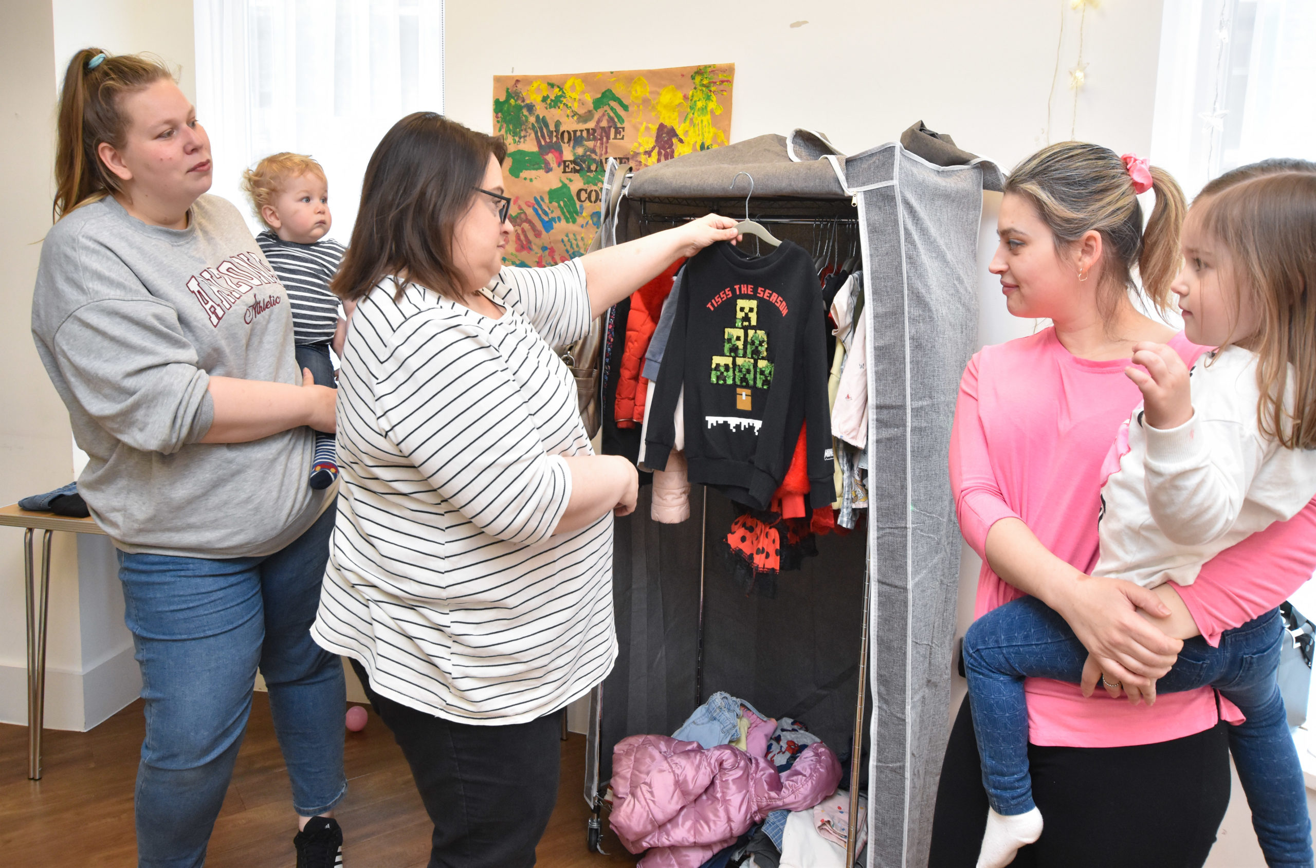 Mel, two mums and their children look through the clothes in the 'Narnia' wardrobe