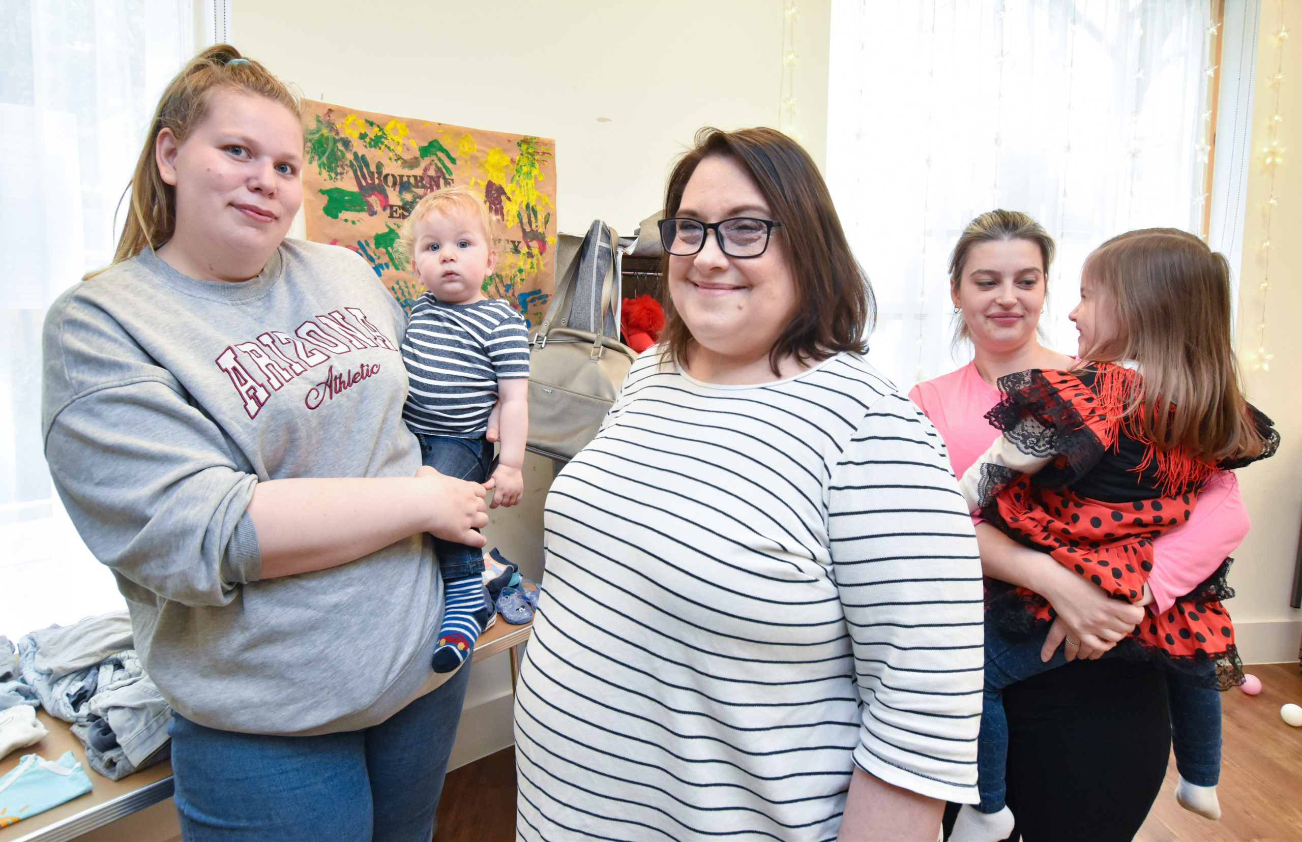 Mel stands with two mums and their children smiling