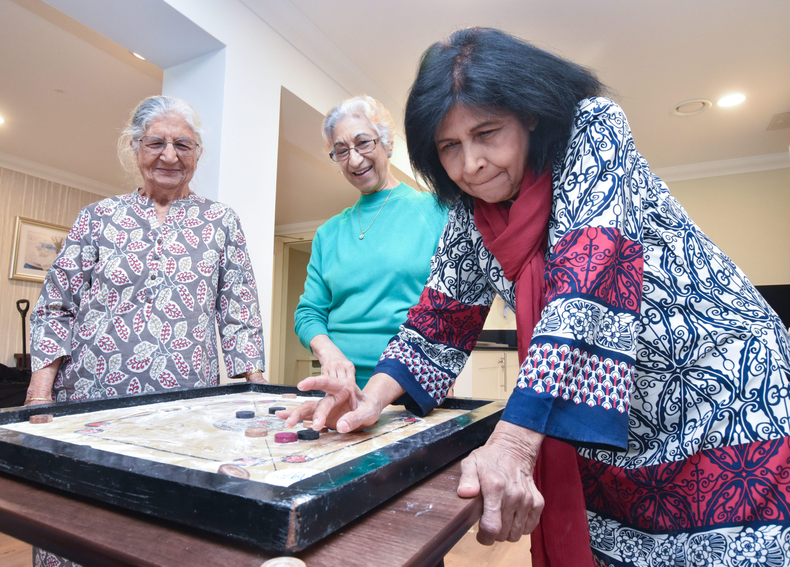 Three members of the Henna group play Carrom - a traditional Indian board game