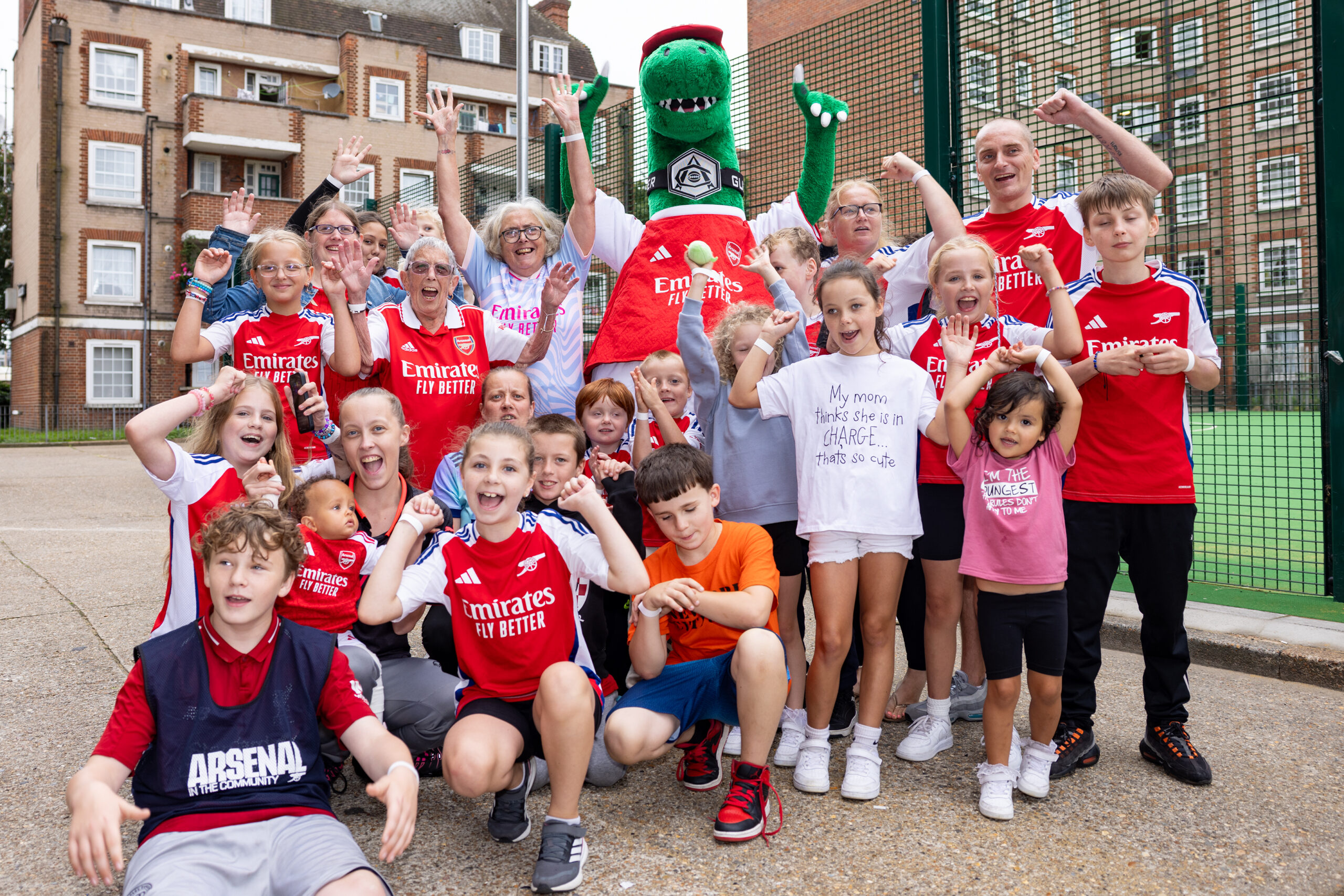 A group of local residents celebrating alongside Arsenal mascot Gunnersaurus