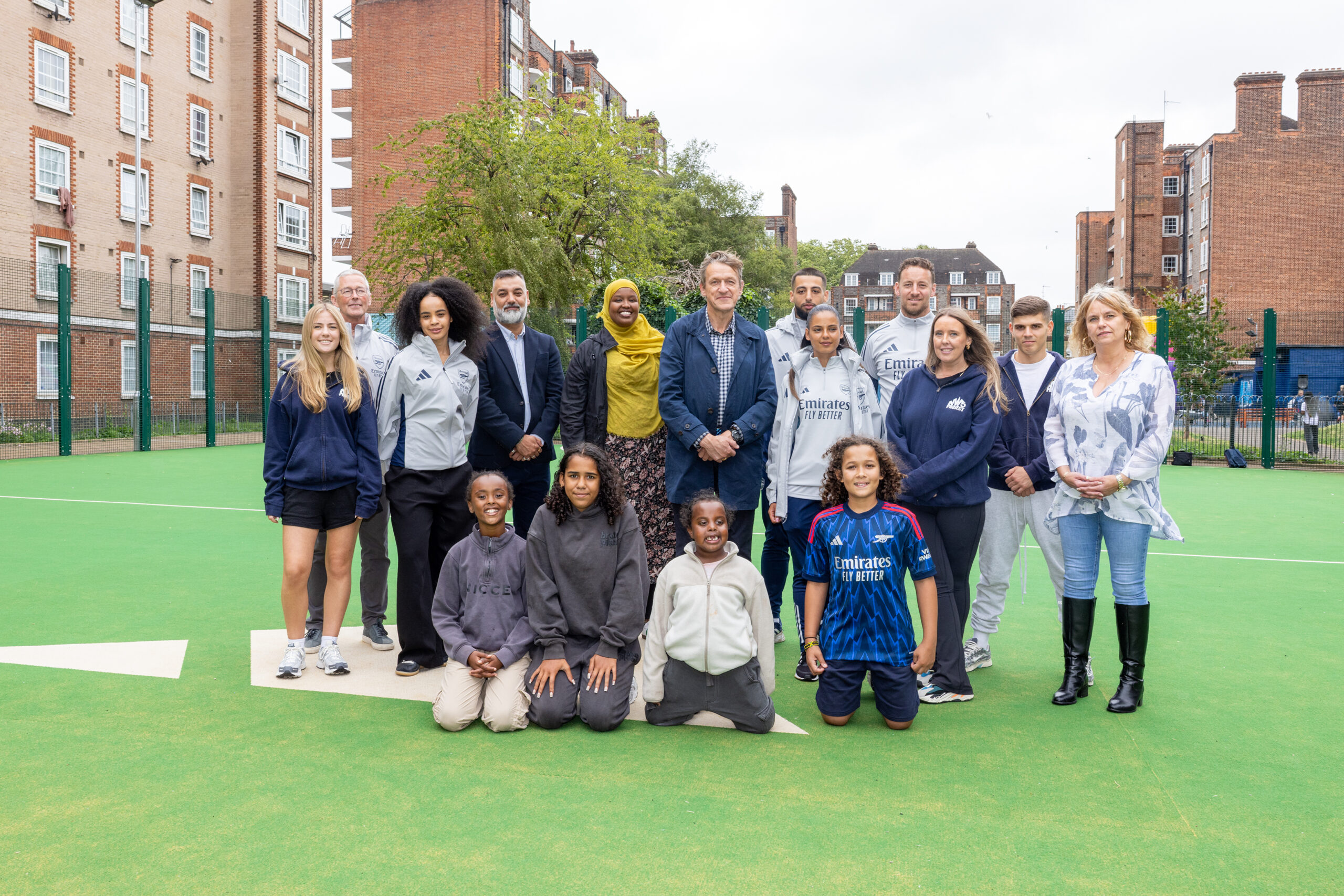 Adults and children posing for a photo on a football pitch