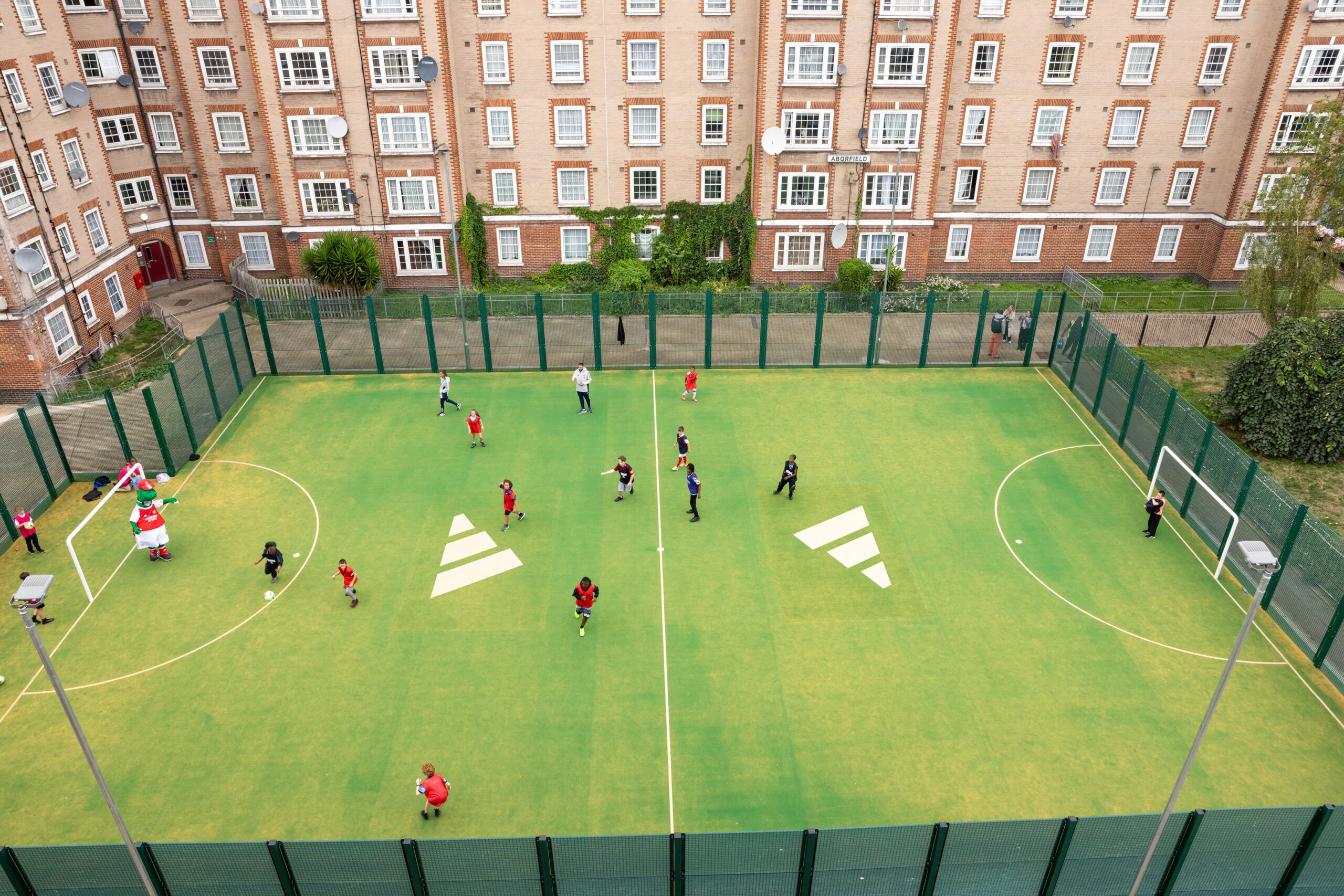 The newly refurbished pitch with local young people playing football.