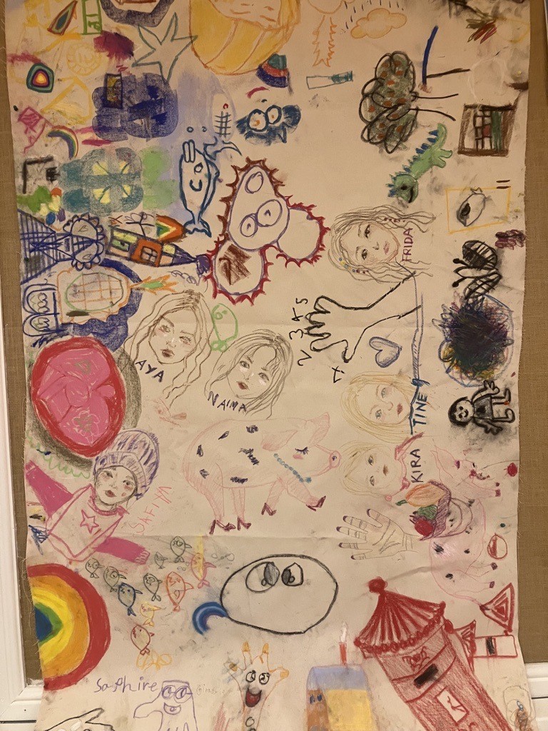 A large sheet filled with children’s colourful drawings, including faces, animals, rainbows, hands, doodles and bright shapes.