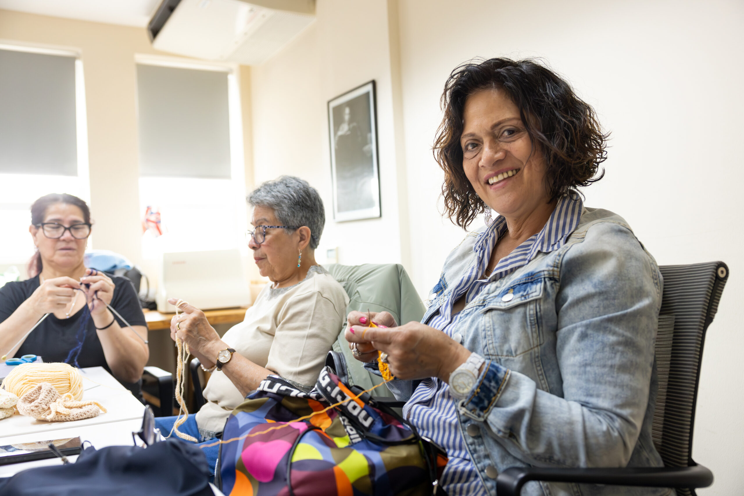 Three women sitting together doing crafts at a table